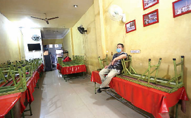 Pedagang warung kopi (Warkop) Jl. H. Misbah, Kel. Hamdan, duduk termenung menunggu pelanggan untuk membeli di warungnya, Rabu (21/7). Sejak PPKM diberlakukandi Kota Medan, berdampak sekali terhadap dagangannya. Dia mengaku hanya dapat menjualdua bungkus mie dan beberapa gelas minuman dingin saja. beritasore/Ist