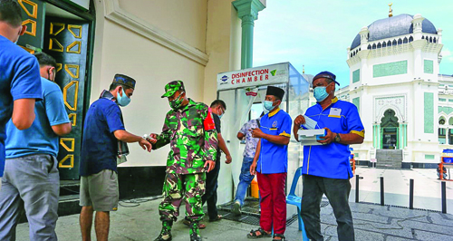 Petugas memeriksa suhu tubuh jamaah yang akan menunaikan shalat Jumat di Masjid Raya Al Mashun Medan, Jumat (16/7). Penerapan protocol kesehatan Covid-19 di masa PPKM Darurat di kota ini diperketat. Waspada/Andy Aditya