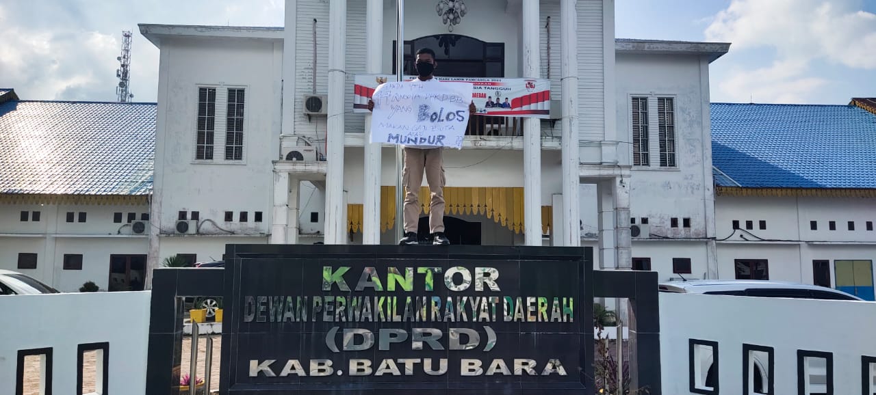 Ahmad Fatih Sultan  membentangkan poster didepan Gedung DPRD Batubara di Limapuluh, Jum'at (2/7/21). beritasore/Alirsyah