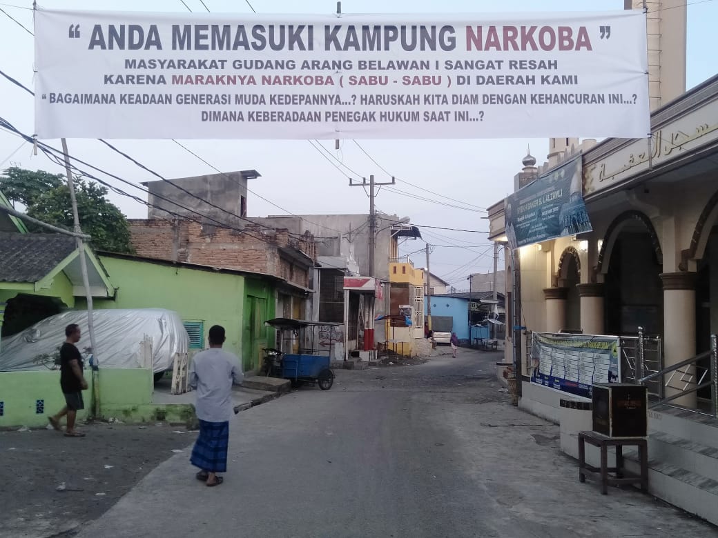 Spanduk bertuliskan Anda Memasuki Kampung Narkoba yang terpasang di depan Masjid Al Aqobah Gudang Arang Kelurahan Belawan I Kecamatan Medan Belawan, Minggu (4/7). beritasore/Ist