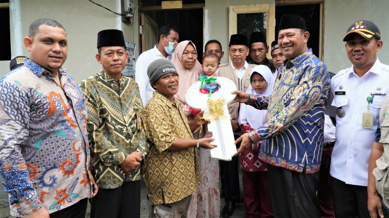 Plt Bupati Langkat H Syah Afandin SH menyerahkan kunci bantuan bedah rumah Baznas Kabupaten Langkat , Rabu (7/9/2022). beritasore/ist
