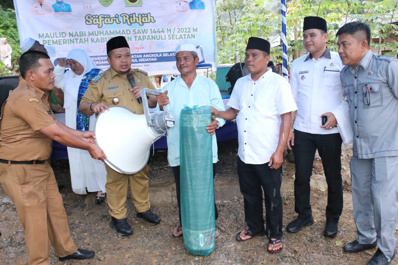 Bupati Tapanuli Selatan (Tapsel) H. Dolly Pasaribu menyerahkan bantuan kepada masyarakat saat menghadiri perayaan maulid Nabi Muhammad SAW sekaligus pengajian Akbar BKMT di Desa Dolok Godang, Kecamatan Angkola Selatan,Selasa (25/10). beritasore/Birong RT