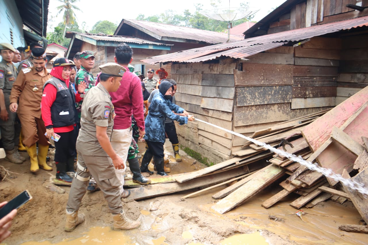 Mensos Bu Risma menyiram lumpur kiriman pasca banjir bandang melanda Kute Rambung Teldak, Selasa (08/11) tepatnya di samping tumpukan kayu olahan milik warga korban banjir. beritasore/Husaini Amin