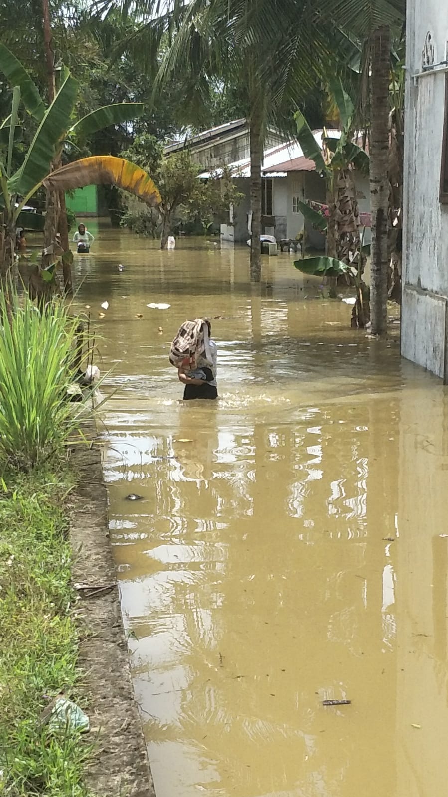 Beritasore/Boy Afrizal: Salah seorang warga sedang melintasi jalan yang tergenang banjir di Desa Securai Utara, Kecamatan Babalan , Kab. Langkat Selasa(22/11/2022).