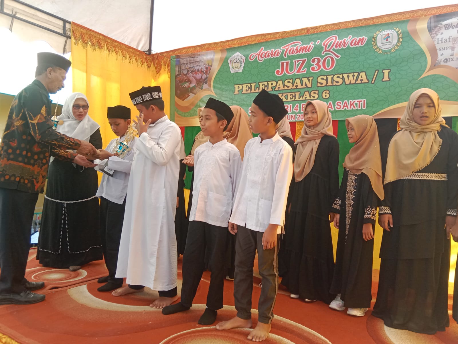 Para murid SDN-4 Banda Sakti, Lhokseumawe yang juga hafidz dan hafidzah berprestasi sedang menerima hadiah dari Kepala Dinas PK Lhokseumawe A. Haris, S.Sos, M.Si yang didampingi Kepala SD setempat Erniati, M.Pd, Sabtu (13/5). Foto: Zainal Abidin