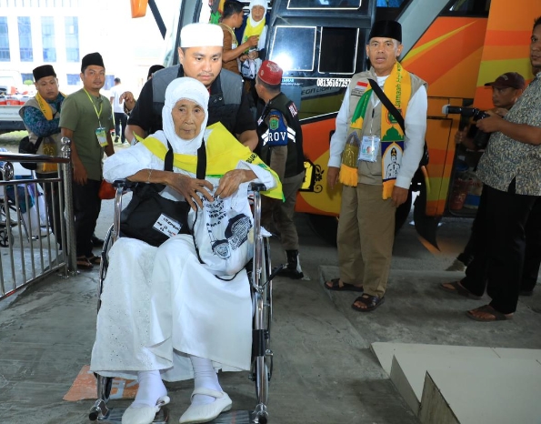 Bupati Labura mendorong kursi roda calhaj Labura di Asrama haji Medan.