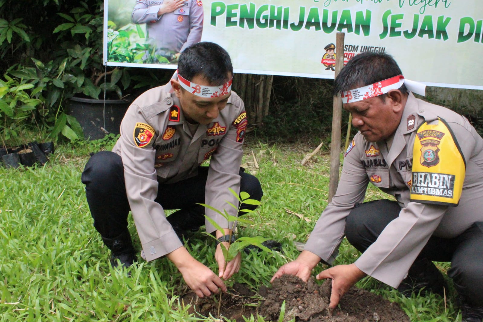 Teks: Kapolsek Medan Baru Kompol Ginanjar Fitriadi yang di dampingi Aiptu Fajar saat menanam pohon