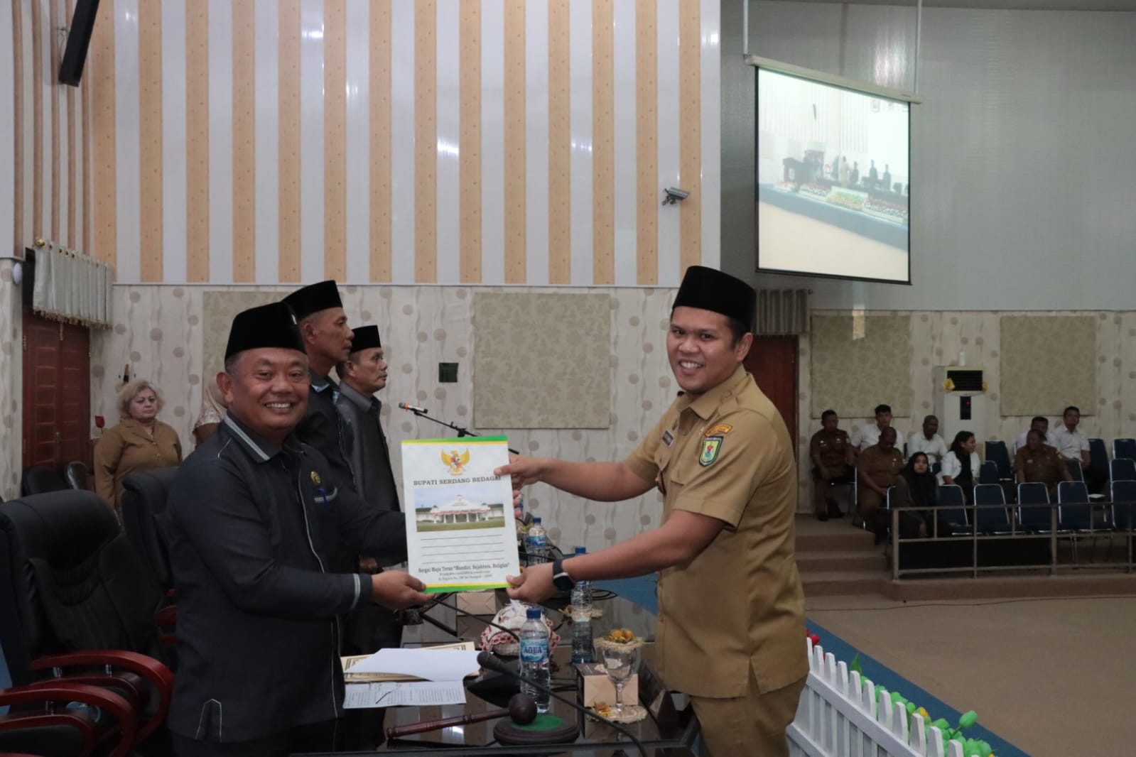 Teks foto: Wakil Bupati Serdang Bedagai H Adlin Tambunan, menyerahkan berkas jawaban Pemerintah Ranperda KLA kepada anggota DPRD Sergai, di aula DPRD, Selasa, 22-08-2023,(Beritasore-Azwen)
