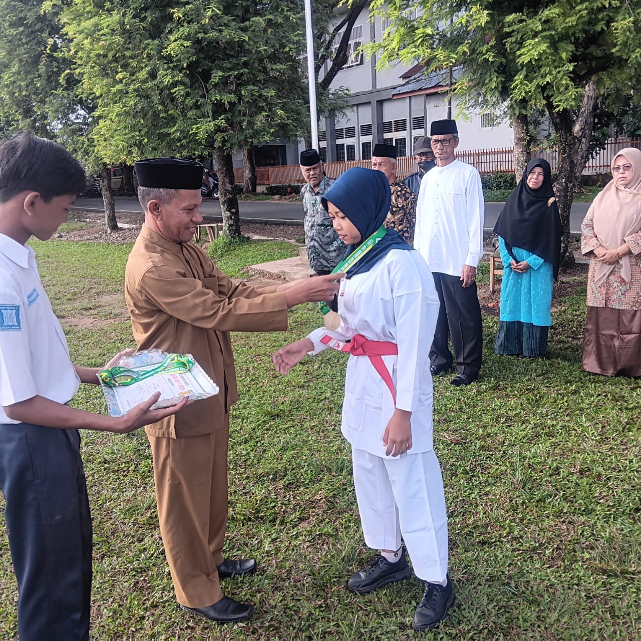 Kepala SMP Negeri 2 Langsa Drs Abdul Mutaleb menyematkan medali penghargaan kepada seorang siswi yang berprestasi Naura Letisya. (Foto:Ibnu Sa'dan).
