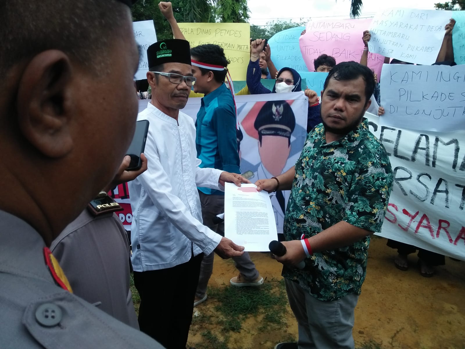 Teks Foto : Arrizal Harahap Menyerahkan Berkas Tuntutan Masyarakat kepada Lahmudin Harahap Kameja Putih Wakil Ketua Badan Permusyawaratan Desa ( BPD) desa Hutaimbaru.Menerima Berkas Tuntunan Masyarakat desa Hutaimbaru