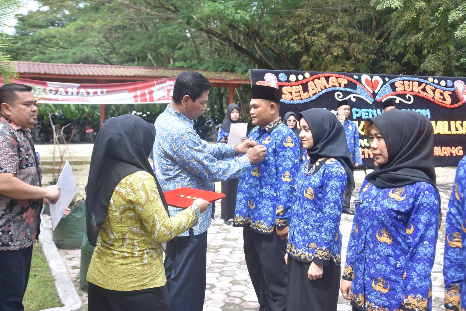 Teks foto : Asisten Pemerintahan, Keistimewaan Aceh dan Kesejahteraan Rakyat, Muslizar, S.Pd, MM saat memasangkan pin Korpri secara simbolis kepada perwakilan peserta penerima SK PPPK.