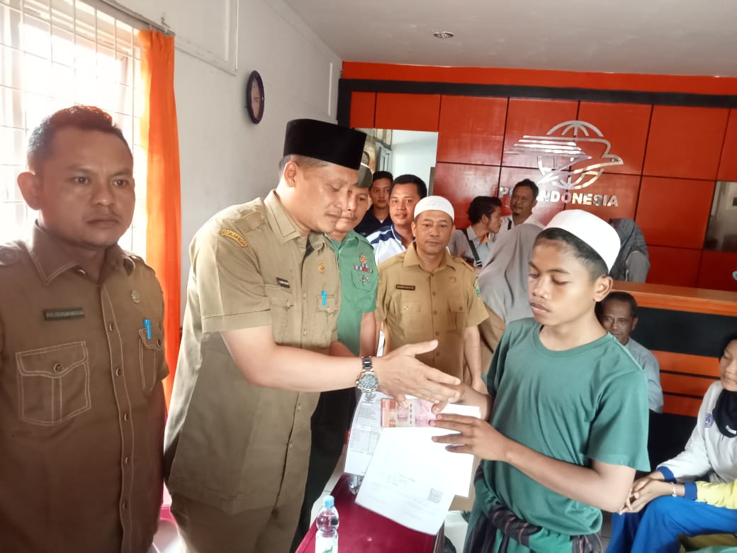 Keterangan Gambar: Kadis Sosial Palas, H Achmad Fauzan Nasution menyerahkan bantuan sosial Kemensos RI kepada anak yatim atau piatu di Kantor POS Sibuhuan, Senin (18/12). Beritasore/Muhammad Satio)