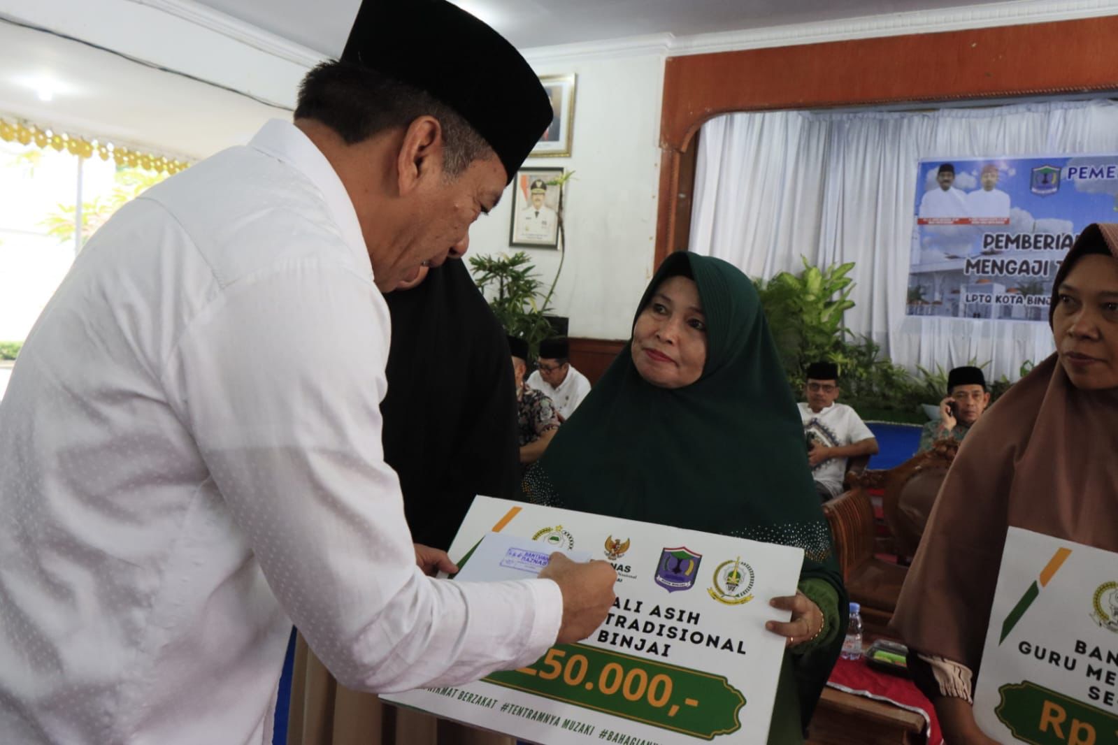 Teks foto: Ketua LPTQ Binjai menyerahkan bantuan. ( Berita/ ist)