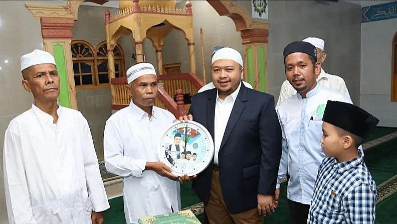 Berita Sore/Birong RT Teks poto: Bupati Tapsel Dolly Pasaribu saat menyerahkan bantuan jam dinding kepada BKM Masjid desa Siuhom Kec.Angkola Barat, Kamis (4/4/2024).