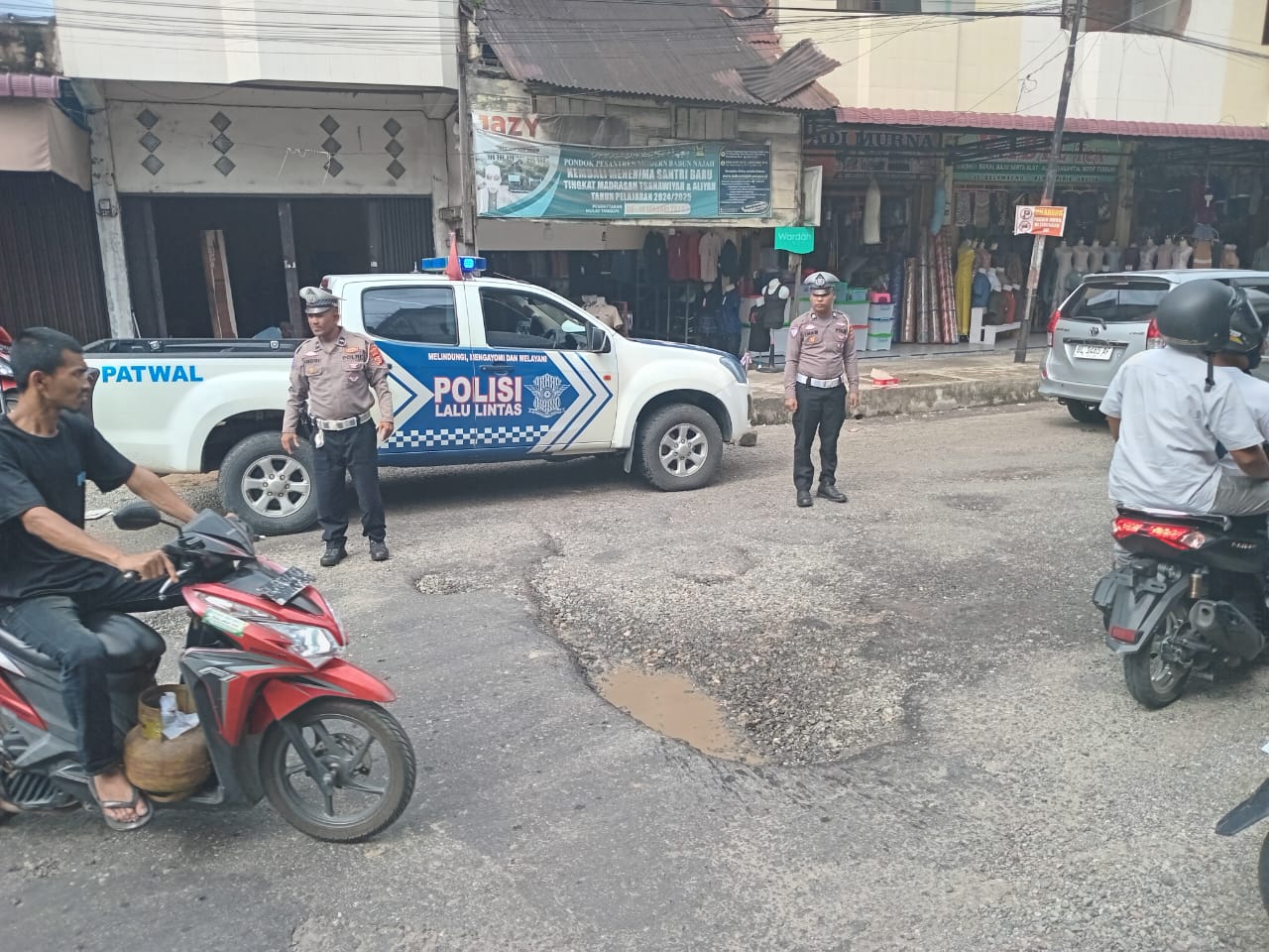 Satlantas Polres Abdya, mengatur arus lalin kendaraan di jalan rusak, kawasan perempatan Jalan Selamat pusat kota Blangpidie. Kamis (6/3).(ist). 