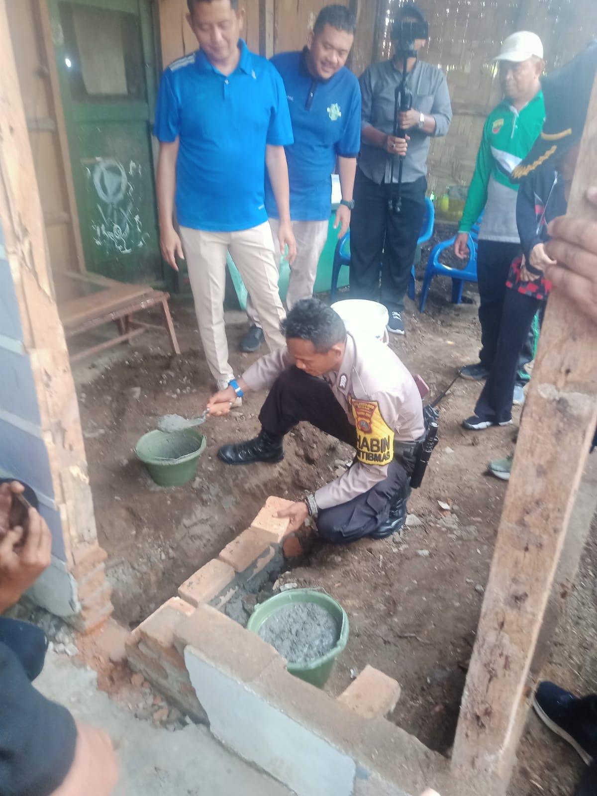 Bhabinkamtibmas Sunggal Bripka Eka saat meletakan batu pelaksanaan Beda rumah di Desa Sei Mencirim