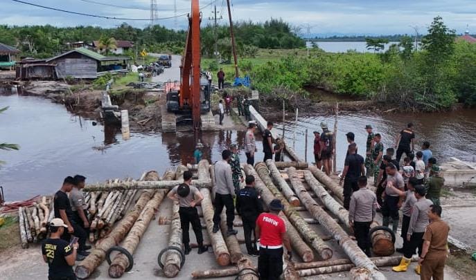 Foto: dengan mengerahkan alat berat serta manual TNI-Polri mengebut pekerjaan pembangunan jembatan dengan batang kelapa, untuk menghubungkan akses menuju Ibukota Kabupaten Aceh Singkil.ist