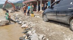 Bekerja : Tampak salah satu alat berat (Escavator), tengah melakukan penimbunan jalan buatan sementara di Kute Lauser Kamis siang (01/01), dibantu sejumlah anggota TNI dan warga ikut merayakan material dilokasi jalan putus . Berita Sore/Husaini Amin