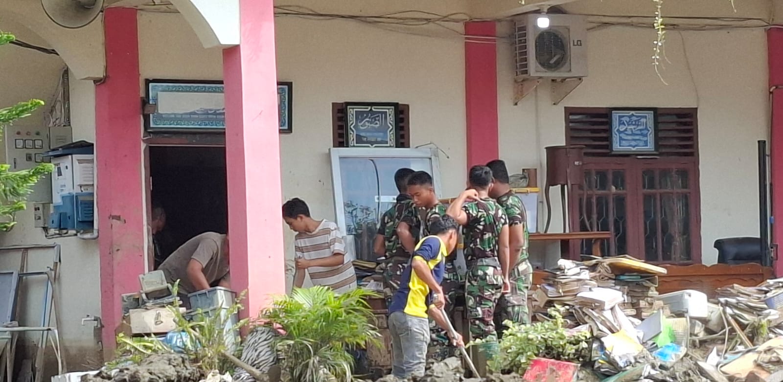 Teks Foto Sejumlah Personil TNI Batalyon Infanteri Tetorial Pembangunan (Yonif TP) 837/ Ksatria Trunojoyo (KT) Kodam V Brawijaya, saat membersihkan lumpur di ruangan Sekolah, Sabtu, (3/1), Foto: Fauzan