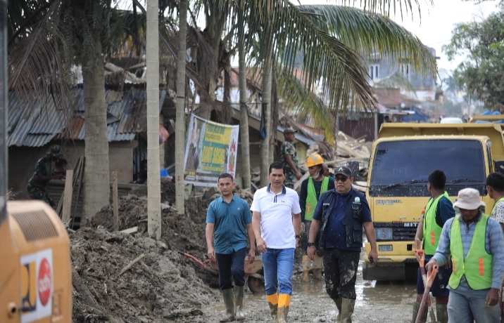 Teks foto: Pemerintah Aceh mengerahkan lima unit alat berat untuk mempercepat proses evakuasi material lumpur tebal dan kayu-kayu gelondongan yang masuk ke area sekolah.Tampak Sekda Aceh, M. Nasir (baju putih) langsung memantau kegiatan tersebut, Senin (05/01/2026). (Ist)